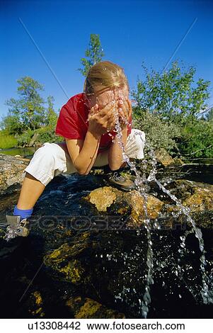 Woman outdoors by a lake splashing water on face View Large Photo Image Stock Image - Woman outdoors by a lake splashing water on face. Fotosearch
