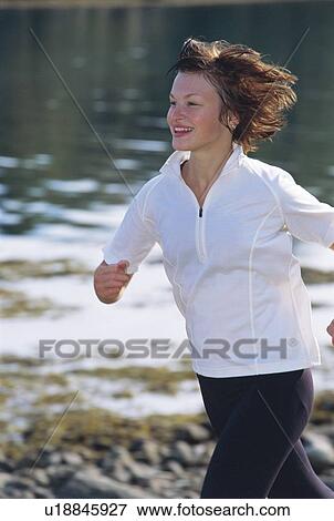 Woman outdoors by a stream running and smiling (selective focus) View Large Photo Image Stock Photo - Woman outdoors by a stream running and smiling (selective focus). Fotosearch