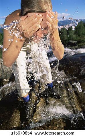Woman outdoors by river splashing water on face (selective focus) View Large Photo Image Picture - Woman outdoors by river splashing water on face (selective focus). Fotosearch
