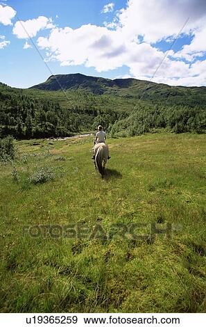Woman outdoors riding horse in scenic location View Large Photo Image Stock Photo - Woman outdoors riding horse in scenic location. Fotosearch