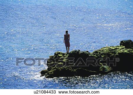 Woman outdoors standing on large rocks by the ocean View Large Photo Image Stock Image - Woman outdoors standing on large rocks by the ocean. Fotosearch
