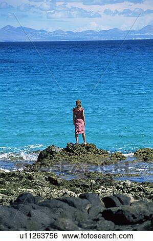 Woman outdoors standing on large rocks Oceanside View Large Photo Image Stock Photograph - Woman outdoors standing on large rocks Oceanside. Fotosearch