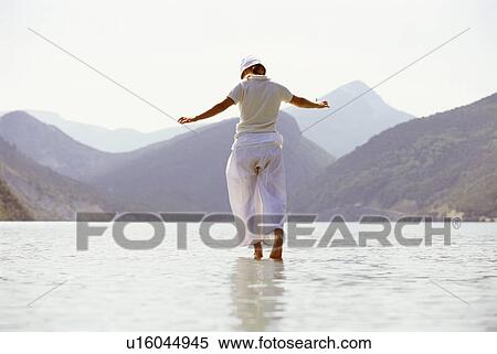 Woman outdoors walking on water in scenic location View Large Photo Image Stock Photography - Woman outdoors walking on water in scenic location. Fotosearch