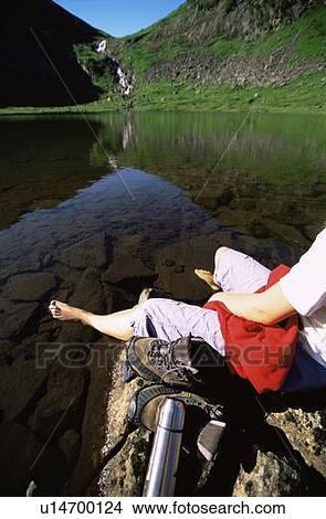 Picture - Woman's legs outdoors at campsite on large rocks. Fotosearch