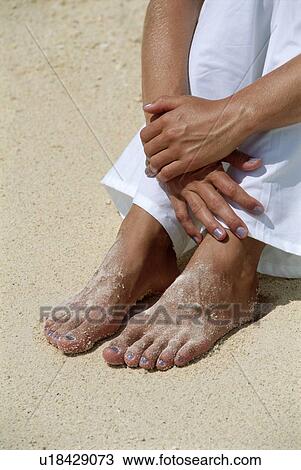 Stock Image - Woman's legs outdoors sitting at the beach. Fotosearch