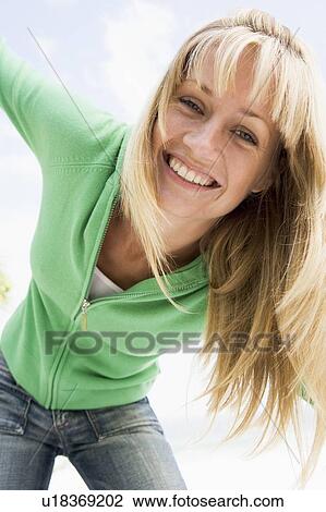 Stock Image - Blonde woman in a green sweater posing outdoors. Fotosearch