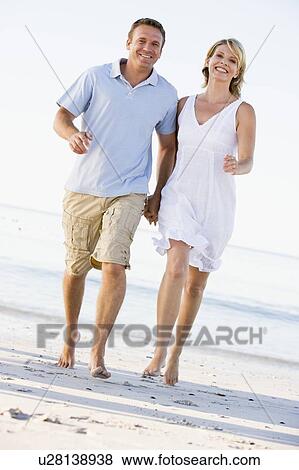 Couple at the beach holding hands and smiling View Large Photo Image Stock Photo - Couple at the beach holding hands and smiling. Fotosearch