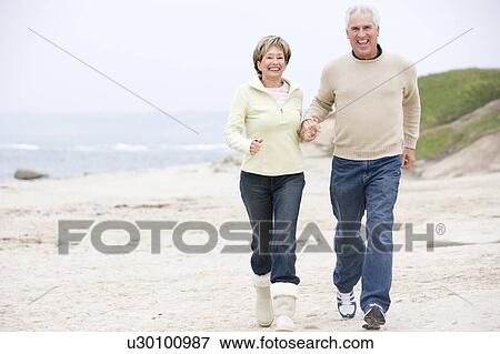 Couple at the beach holding hands and smiling View Large Photo Image Stock Photo - Couple at the beach holding hands and smiling. Fotosearch