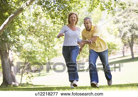 Couple running outdoors in park and smiling View Large Photo Image Stock Photo - Couple running outdoors in park and smiling. Fotosearch