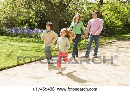 Stock Photo - Family running on path holding hands smiling. Fotosearch