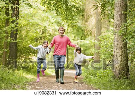 Father and daughters walking on path holding hands smiling View Large Photo Image Stock Image - Father and daughters walking on path holding hands smiling. Fotosearch