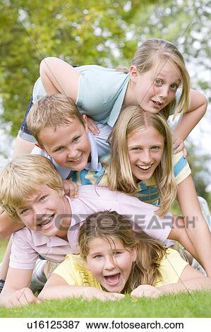 Five young friends piled on each other outdoors smiling View Large Photo Image Stock Photo - Five young friends piled on each other outdoors smiling. Fotosearch