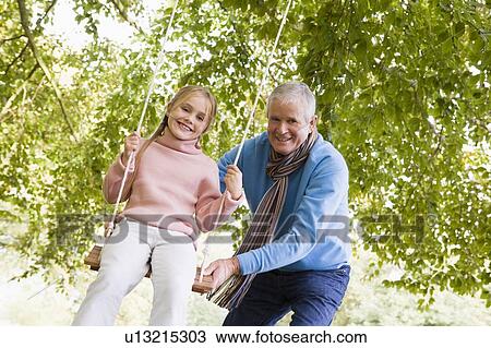 Grandfather pushing granddaughter on swing and smiling (selective focus) View Large Photo Image Stock Image - Grandfather pushing granddaughter on swing and smiling (selective focus). Fotosearch