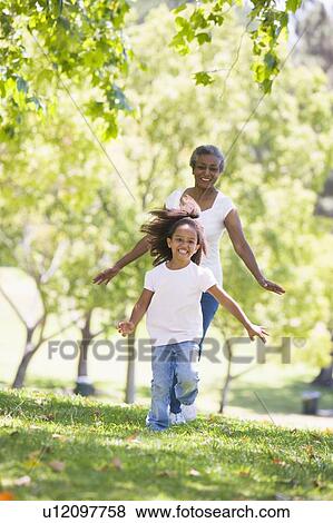 Grandmother and granddaughter running in park and smiling View Large Photo Image Stock Photo - Grandmother and granddaughter running in park and smiling. Fotosearch