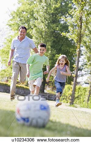 Man and two young children outdoors playing soccer and having fun View Large Photo Image Stock Photograph - Man and two young children outdoors playing soccer and having fun. Fotosearch