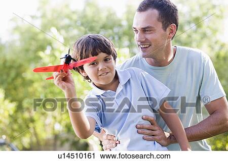 Man and young boy outdoors playing with toy airplane smiling View Large Photo Image Stock Image - Man and young boy outdoors playing with toy airplane smiling. Fotosearch