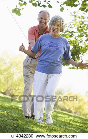 Stock Image - Senior couple walking in park together. Fotosearch