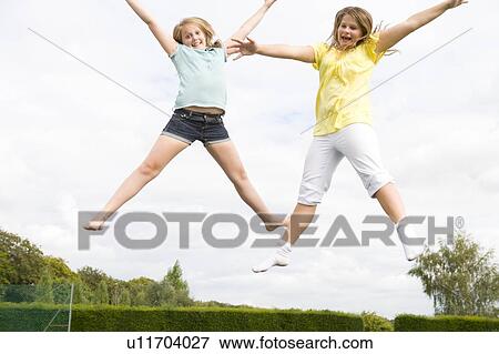 Two young girls jumping on trampoline smiling View Large Photo Image Stock Photo - Two young girls jumping on trampoline smiling. Fotosearch