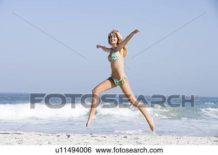 Woman in a two piece bathing suit running on a beach View Large Photo Image Stock Photograph - Woman in a two piece bathing suit running on a beach. Fotosearch