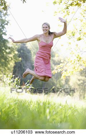 Stock Image - Woman jumping in a park. Fotosearch