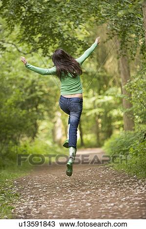 Stock Image - Woman jumping on path. Fotosearch