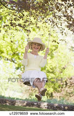 Stock Photo - Woman on a swing outdoors smiling. Fotosearch