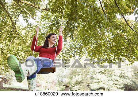 Woman outdoors swinging on tree swing and smiling (selective focus) View Large Photo Image Stock Photo - Woman outdoors swinging on tree swing and smiling (selective focus). Fotosearch