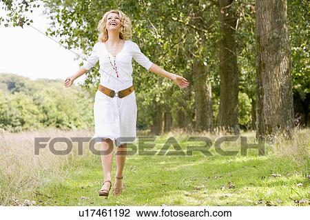 Stock Image - Woman walking on path smiling. Fotosearch