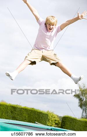 Young boy jumping on trampoline smiling View Large Photo Image Stock Photograph - Young boy jumping on trampoline smiling. Fotosearch