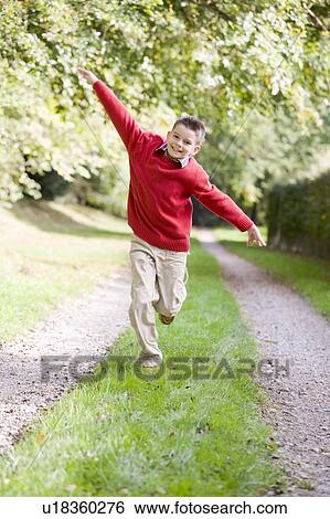 Young boy running on a path outdoors smiling View Large Photo Image Stock Photograph - Young boy running on a path outdoors smiling. Fotosearch