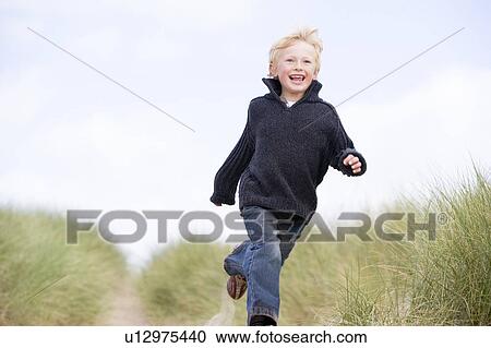 Young boy running on beach smiling View Large Photo Image Stock Image - Young boy running on beach smiling. Fotosearch
