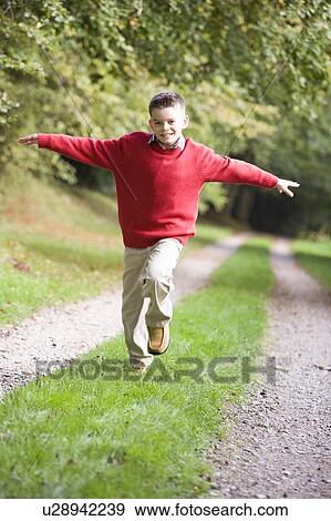 Young boy running on path outdoors smiling (selective focus) View Large Photo Image Stock Photo - Young boy running on path outdoors smiling (selective focus). Fotosearch