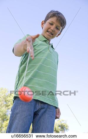 Stock Image - Young boy using yo yo outdoors smiling. Fotosearch