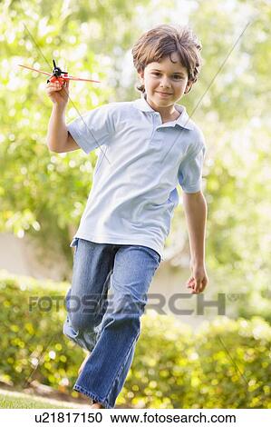 Young boy with toy airplane running outdoors smiling View Large Photo Image Stock Image - Young boy with toy airplane running outdoors smiling. Fotosearch