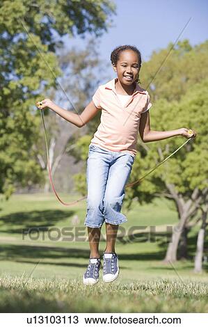 Young girl using skipping rope outdoors smiling View Large Photo Image Stock Image - Young girl using skipping rope outdoors smiling. Fotosearch