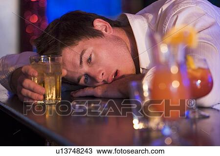 Stock Image - Drunk young man passed out in bar. Fotosearch