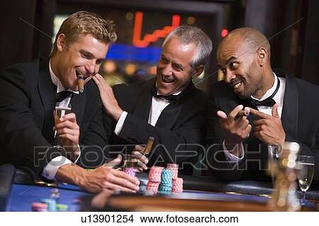 Picture - Three men in casino playing roulette and smiling (selective focus). Fotosearch
