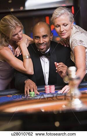 Three people in casino playing roulette smiling (selective focus) View Large Photo Image Stock Image - Three people in casino playing roulette smiling (selective focus). Fotosearch