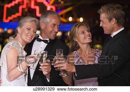 Two couples in casino toasting champagne smiling (selective focus) View Large Photo Image Stock Photo - Two couples in casino toasting champagne smiling (selective focus). Fotosearch