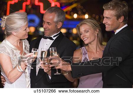 Stock Photograph - Two couples in casino toasting champagne smiling (selective focus). Fotosearch