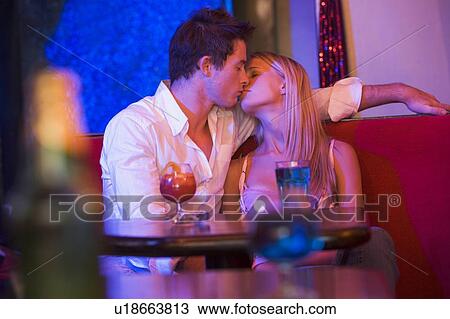 Stock Image - Young couple kissing in a bar. Fotosearch