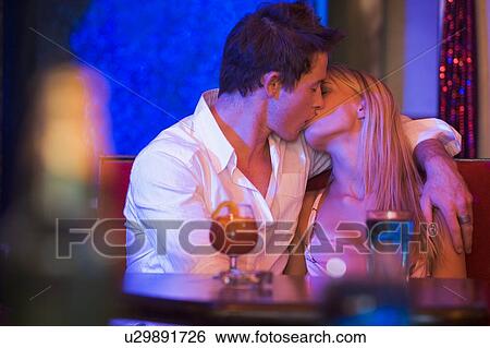 Stock Photograph - Young couple kissing in a bar. Fotosearch