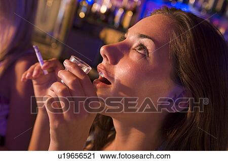 Stock Image - Young woman in a bar smoking. Fotosearch