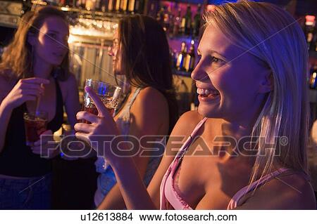 Picture - Young woman in a bar with friends. Fotosearch