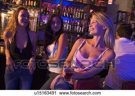 Stock Image - Young woman in a bar with friends. Fotosearch