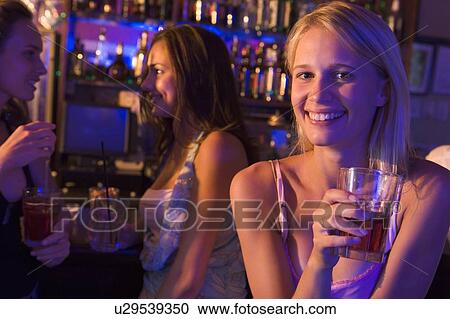 Young woman in a bar with friends View Large Photo Image Stock Image - Young woman in a bar with friends. Fotosearch