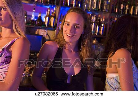 Stock Photography - Young woman in a bar with friends. Fotosearch