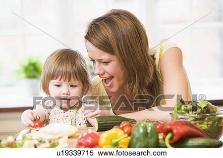 Stock Photography - Mother and daughter in kitchen making a salad smiling. Fotosearch