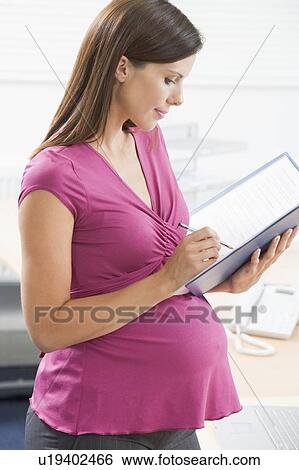 Pregnant woman at work writing in binder View Large Photo Image Stock Photograph - Pregnant woman at work writing in binder. Fotosearch