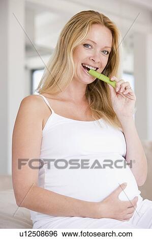 Pregnant woman eating celery and smiling View Large Photo Image Stock Photograph - Pregnant woman eating celery and smiling. Fotosearch